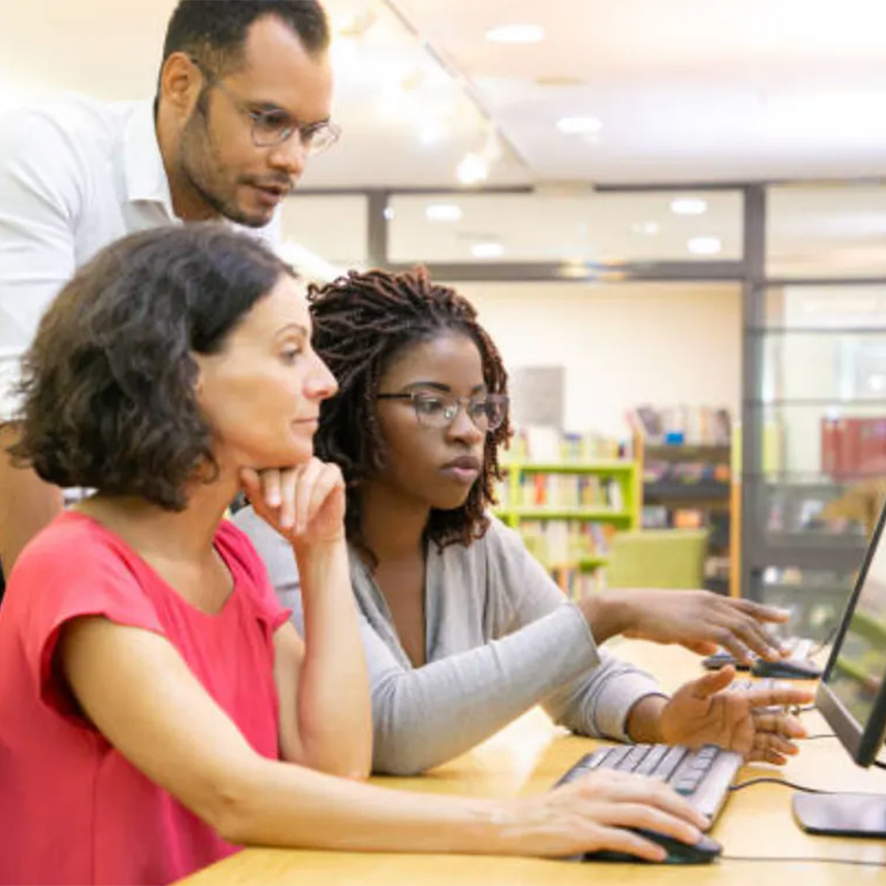 people working at a computer with someone looking over their shoulders